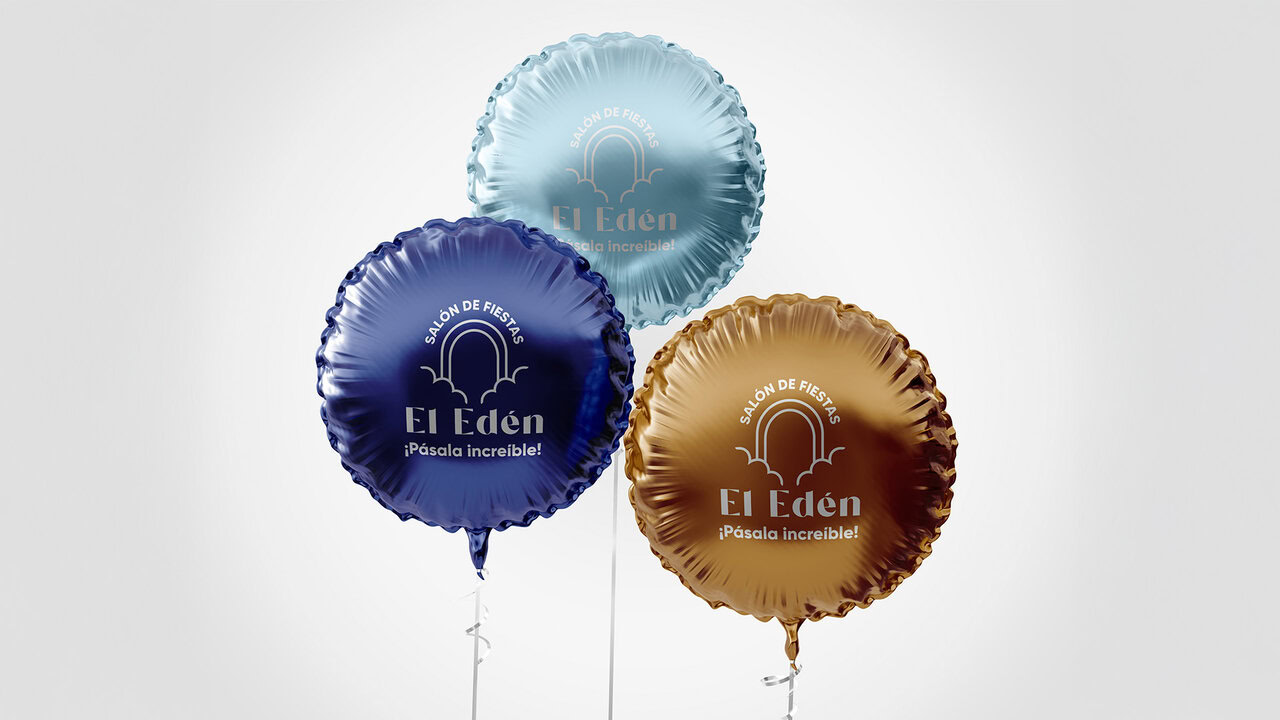 Nebly_ELEDEN_Globos_3 Tres globos metálicos (azul, dorado y plateado) con el logotipo de El Edén Salón de Fiestas y el eslogan '¡Pásala increíble!'. Artículos promocionales para eventos.