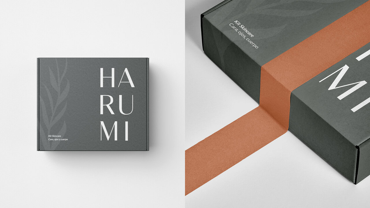 Nebly_Harumi_Ecommerce_1920x1080 Cajas de productos Harumi, mostrando el diseño de empaque minimalista. Color gris oscuro con el logotipo y una ilustración de hojas. Branding para cosmética natural.